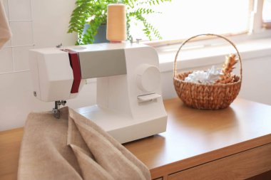 Terzi atölyesinde dikiş makinesi ve kumaş olan masa.