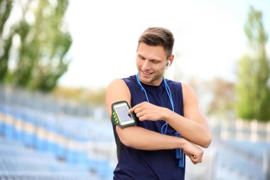 Stadyumda cep telefonu kullanan genç bir adam.