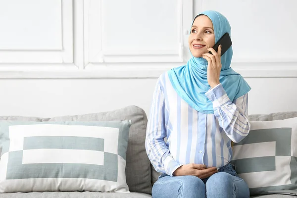 妊娠中のイスラム教徒の女性が家で携帯電話で話す — ストック写真