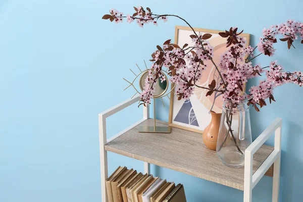 カラーウォールの近くに花の枝を持つ本棚 — ストック写真