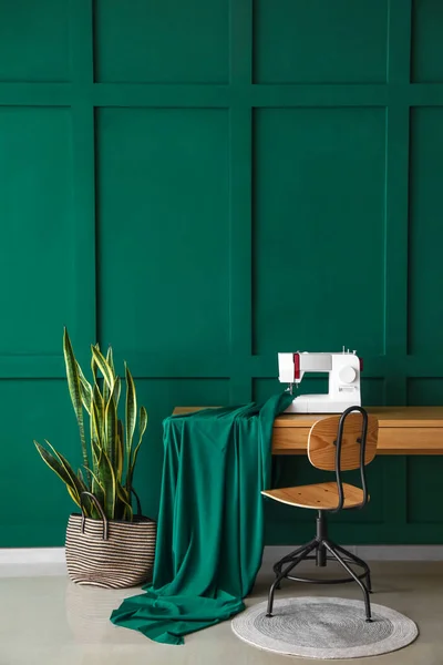 裁缝机 布和家用植物在绿墙附近的裁缝工作场所 — 图库照片