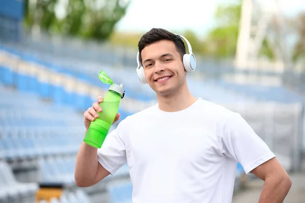 在体育场 一个戴着耳机 头戴瓶装水的矮胖年轻人 — 图库照片