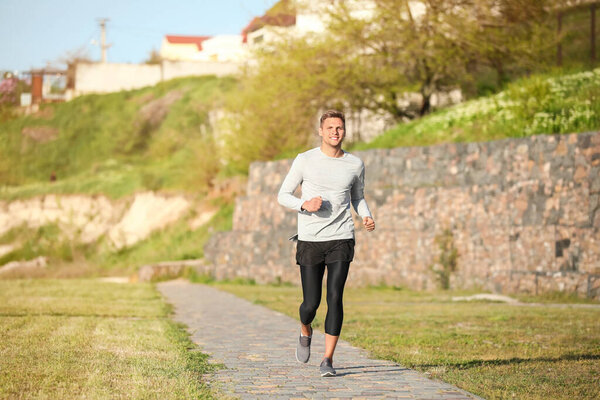 Спортивный молодой человек бегает в парке