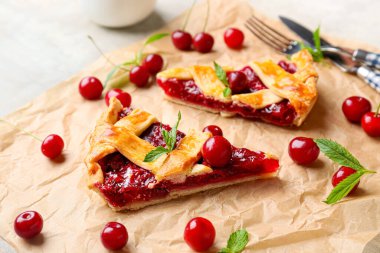 Açık arkaplanda lezzetli vişneli turta parçaları olan parşömen, yakın plan.