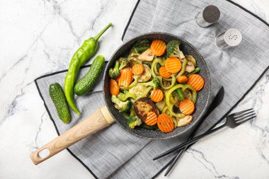 Farklı sebzelerle kızartma tavası ve hafif arka planda baharatlar.