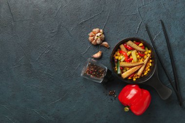 Kızartma tavasında farklı sebzeler ve arka planda farklı baharatlar içeren kompozisyon