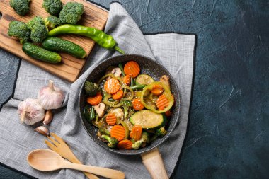 Koyu arka planda farklı sebzelerle kızartma tavası.