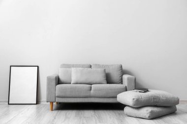 Oturma odasındaki ahşap zeminde yastıkları olan rahat bir kanepe.