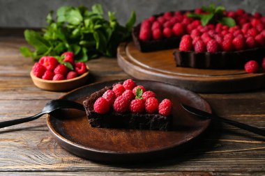 Bir parça lezzetli ahududu turtası ve nane şekeri ile ahşap masa, yakın plan.