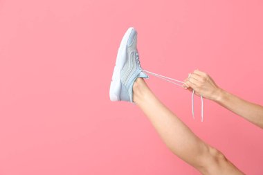 Arka planda ayakkabı bağcıkları bağlayan genç kadın.