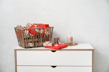 Noel takviminde hediye kutuları sepette ve beyaz duvarın yanındaki çekmecelerde bir fincan kakao.