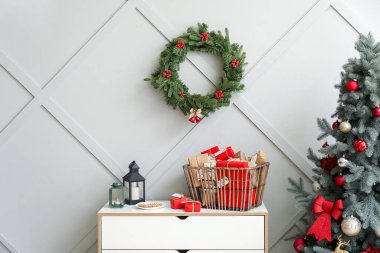 Sepetinde hediye kutuları, çekmecesinde mumlar ve duvarında Noel çelengi olan bir takvim.