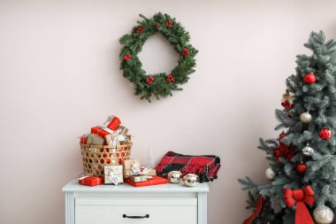 Sepette hediye kutuları, mumlar, çekmecelerde ekose ve renkli duvarlarda Noel çelengi olan bir takvim.