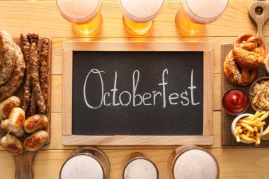Soğuk bira bardakları, karatahta, tahtalar Bavyera sosisleri ve ahşap arka planda atıştırmalıklar. Ekim Festivali Kutlaması