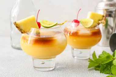 Kiraz ve ananas dilimleriyle süslenmiş şık bir Mai Tai kokteyli.