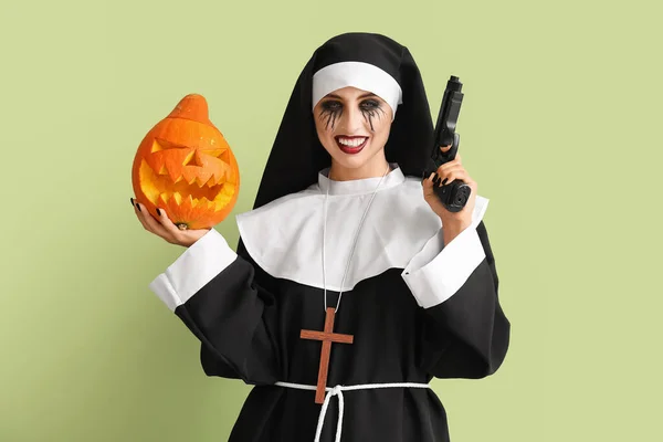 女は修道女としてハロウィンのために服を着て銃とカボチャの色の背景 — ストック写真