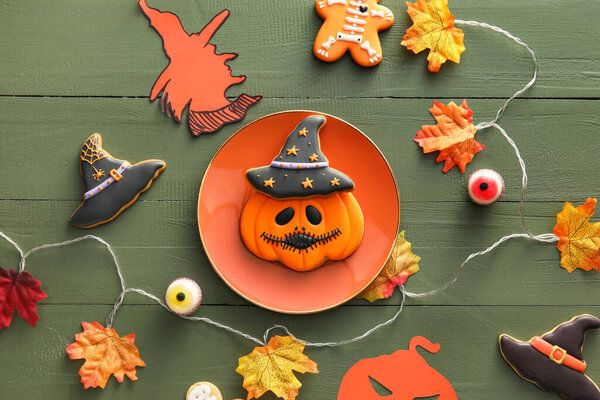 Tasty cookies for Halloween celebration with decor on color wooden background