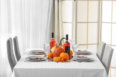 Şenlikli servis masasında şarap şişeleri ve sonbahar süslemeleri var.