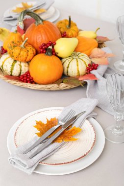 Tabakta çatal bıçak, peçete ve sonbahar yaprağı var.