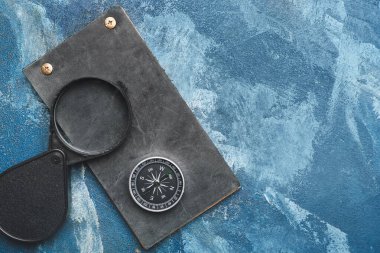 Renk arkaplanı üzerinde pusula, defter ve büyüteç