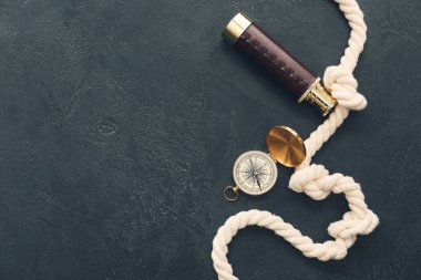 Koyu arkaplanda klasik pusula, dürbün ve ip