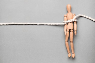 Gri arka planda ipe bağlı bir manken. Rehine kavramı