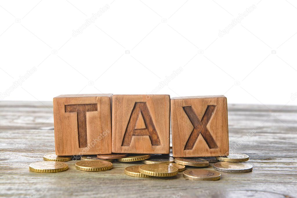 Word TAX with coins on table against white background