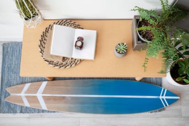 Sörf tahtası ve masası olan şık bir odanın içi.