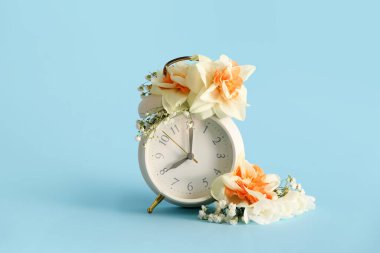 Mavi arka planda güzel çiçekli çalar saat. Bahar zamanı konsepti