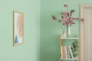 Renk duvarının yanında çiçek açan dalları olan bir kitaplık.