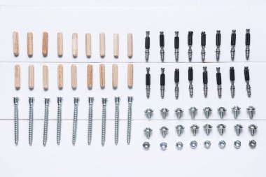 Beyaz ahşap arka planda cıvatalar, fındıklar ve paneller