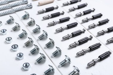 Beyaz ahşap masadaki civata, fındık ve pervazlar, yakın plan.