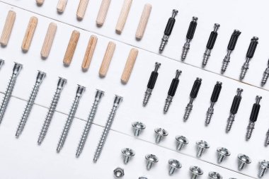 Beyaz ahşap arka planda cıvatalar, fındıklar ve paneller, yakın plan