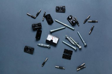 Koyu arkaplanda analog termostat, köşe ayraçları, cıvatalar ve vidalar