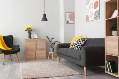 Aydınlık oturma odasının içinde siyah kanepe ve koltuk