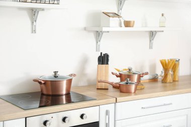 Bakır tencereler, çiğ makarna ve bıçaklar mutfakta.