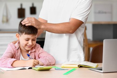Babasıyla evde ders alan küçük bir çocuk.