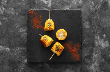 Siyah arka planda lezzetli ızgara Meksika sokak mısırı parçaları olan tahta.