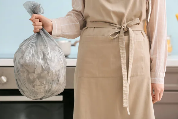 Woman holding bag with garbage at home, closeup