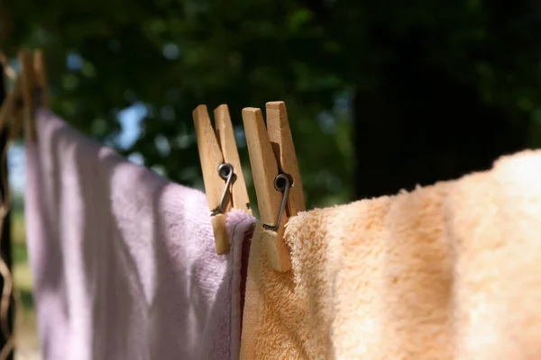 Towels with clothespins hanging on laundry line outdoors, closeup