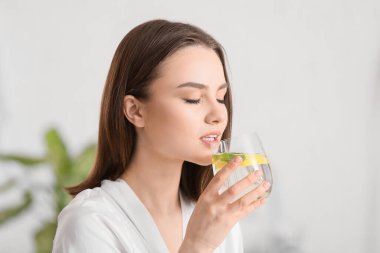 Güzel genç bayan evde taze limonata içiyor.