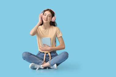 Tablet bilgisayarlı genç bir kadın renkli arka planda sesli kitap dinliyor