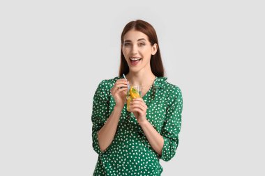 Gri arka planda taze limonatası olan güzel genç bir kadın.