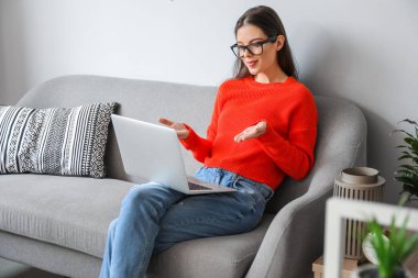 Genç bir kadının evde görüntülü konuşması.