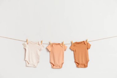 Beyaz arka planda ipte sallanan farklı bebek kıyafetleri