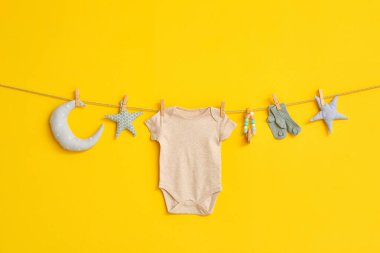 Bebek kıyafeti, çoraplar ve oyuncaklar ipe asılı renk arka planında