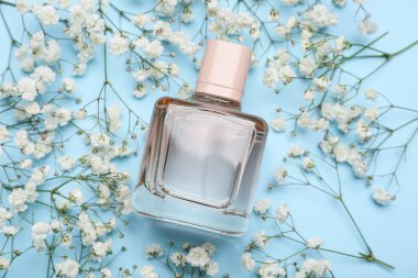 Renkli arka planda parfüm şişesi ve çigila çiçekli kompozisyon, yakın plan.