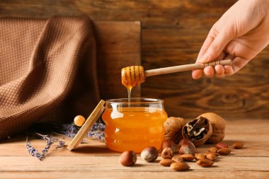 Tatlı bal kavanozu ve ahşap arka planda Dipper 'la el.