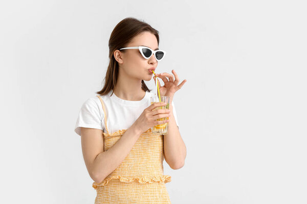 Красивая молодая женщина пьет свежий лимонад на белом фоне
