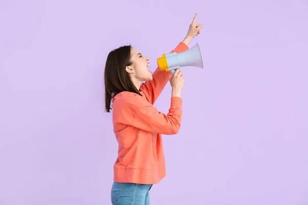 Protesting young woman with megaphone on color background